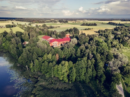 Aerial Photo of Old Castle turned into School in Countryside Between Trees with Dramatic Clouds over it in Early Spring on Sunny Day - Concept of Peaceful Life in Countryside in Harmony, Vintage Lookのeditorial素材