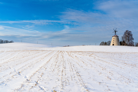 Empty Countryside Landscape in Sunny Winter Day with Snow Covering the Ground with Big Abandoned Windmill in Background - Concept of Fun and Joyの写真素材