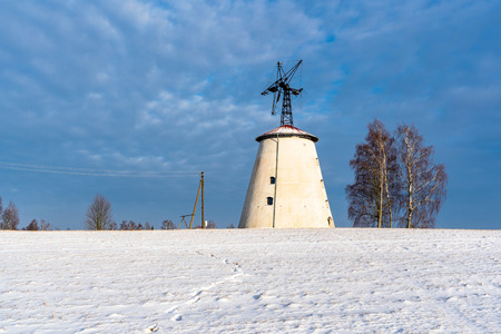 Empty Countryside Landscape in Sunny Winter Day with Snow Covering the Ground with Big Abandoned Windmill in Background - Concept of Fun and Joyの写真素材