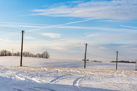 Empty Countryside Landscape in Sunny Winter Day with Snow Covering the Ground with Power Lines in Frame, Abstract Background - Concept of Fun and Joyの写真素材