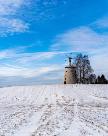 Empty Countryside Landscape in Sunny Winter Day with Snow Covering the Ground with Big Abandoned Windmill in Background - Concept of Fun and Joyの写真素材