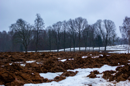 Empty Countryside Landscape in Cloudy Winter Day with Snow Partly Covering the Ground and Fog - Concept of Sadness and Lonelinessの写真素材