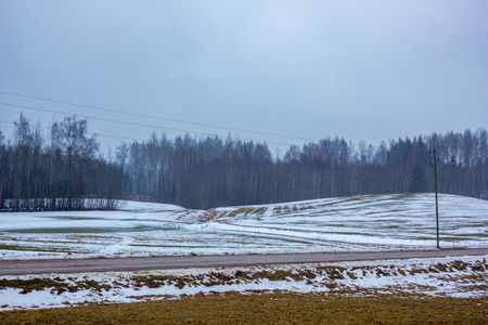 Empty Countryside Landscape in Cloudy Winter Day with Snow Partly Covering the Ground and Fog - Concept of Sadness and Lonelinessの写真素材
