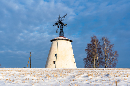 Empty Countryside Landscape in Sunny Winter Day with Snow Covering the Ground with Big Abandoned Windmill in Background - Concept of Fun and Joyの写真素材