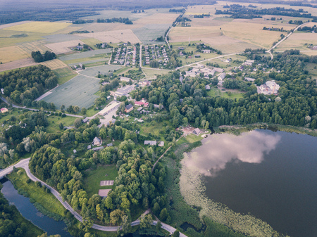 Aerial Photo of Countryside Village Between Trees and with Big Blue Lake Besides it in Early Spring on Sunny Day - Concept of Peaceful Life in Countryside in Harmony, Vintage Film Lookの写真素材