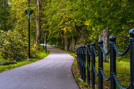 Colorful Photo of the Road in a Park, Between Woods - Closeup view of the Chain Fence with Blurred Background with Space for Text, Sunny Autumn day, Concept of the Peace and Harmonyの写真素材