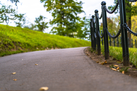 Colorful Photo of the Road in a Park, Between Woods - Closeup view of the Chain Fence with Blurred Background with Space for Text, Sunny Autumn day, Concept of the Peace and Harmonyの写真素材