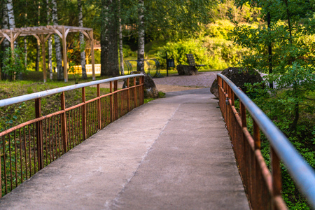 Colorful Photo of the Bridge in a Park, Between Woods - with Blurred Park Benches in the Background with Space for Text, Sunny Autumn day, Concept of Peace and Harmonyの写真素材