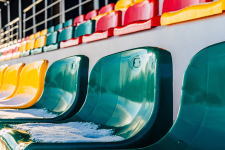 Closeup of Empty Colorful Football (Soccer) Stadium Seats in the Winter Covered in Snow - Sunny Winter Day, Concept of Winter Sports and Gameの写真素材