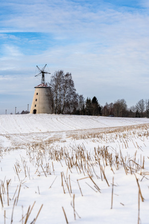 Empty Countryside Landscape in Sunny Winter Day with Snow Covering the Ground with Big Abandoned Windmill in Background - Concept of Fun, Joy and Travelの写真素材