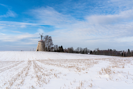 Empty Countryside Landscape in Sunny Winter Day with Snow Covering the Ground with Big Abandoned Windmill in Background - Concept of Fun, Joy and Travelの写真素材