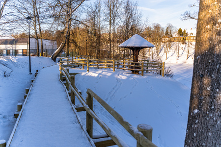 Snowy Photo of the Park on a Sunny Winter day - Wooden Footpath in the Middle of it, Concept of the Harmony and Travel in the Countrysideの写真素材