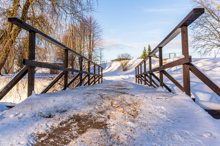 Snowy Photo of the Park on a Sunny Winter day - Wooden Bridge in the Middle of it, Concept of the Harmony and Travel in the Countrysideの写真素材