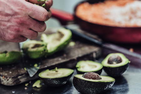 Male Chef Pealing Avocado for Wedding Meal - Kitchen Set with Isolated Action, Only Chef`s Hands,...