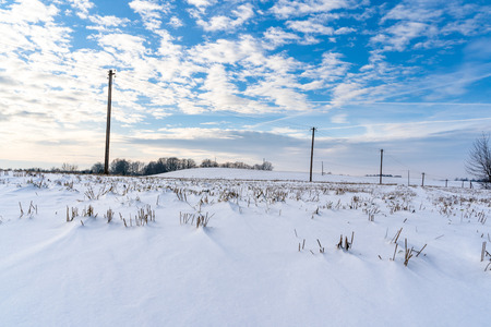 Empty Countryside Landscape in Sunny Winter Day with Snow Covering the Ground with Power Lines in Frame, Abstract Background with Deep Look - Concept of Fun and Joyの写真素材