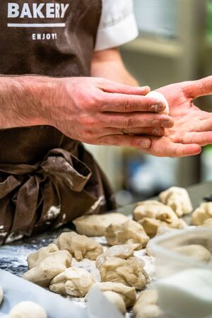 Male Chef Preparing Bread Dough for Selfmade Bread and Patties - Kitchen Set with Isolated Action, Only Chef`s Hands, Text on Apron "Bakery, Enjoy"のeditorial素材