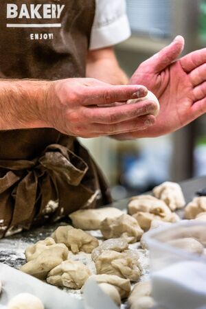 Male Chef Preparing Bread Dough for Selfmade Bread and Patties - Kitchen Set with Isolated Action, Only Chef`s Hands, Text on Apron "Bakery, Enjoy"のeditorial素材