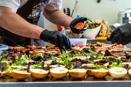 Odziena / Latvia - August 24th, 2018: Male Chef Putting Ingredients of Burgers in Black Gloves - Concept of the Hard Working Person and the Hygiene in the Kitchen, Partly Blurred Foregroundのeditorial素材