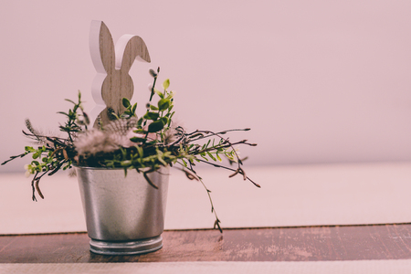 Isolated Handmade Easter Decorations (Bunny with Blossom Flowers in a Bucket on Table), Space for Text or Company Logo - Concept of the Harmony and Peace in Family on Festive Timeの写真素材