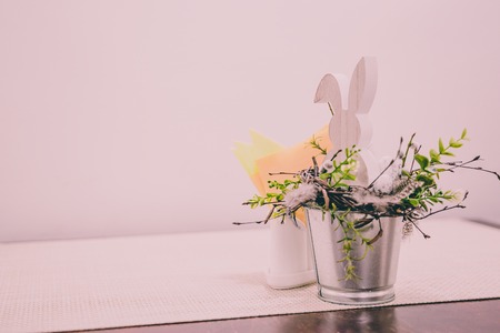 Isolated Handmade Easter Decorations (Wooden Bunny with Blossom Flowers in a Bucket on Table), Space for Text or Company Logo - Concept of the Harmony and Peace in Family on Festive Timeの写真素材