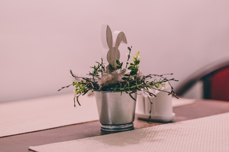 Isolated Handmade Easter Decorations (Bunny with Blossom Flowers in a Bucket on Table), Space for Text or Company Logo - Concept of the Harmony and Peace in Family on Festive Timeの写真素材