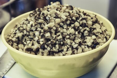 Chopped cucumber pieces in yellow plastic bowl on table, isolated close up photoの写真素材