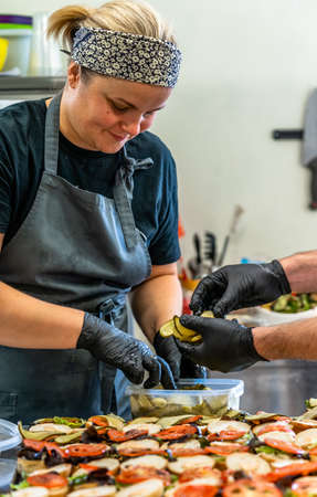 Female Chef Putt Ingredients of Burgers on Sliced Bread Spread with Black Gloves - Concept of the Hard Working Person and the Hygieneの写真素材