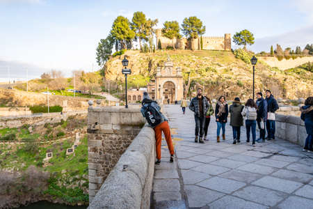 Toledo / Spain - January 23rd, 2020 Tourists Walking over Alcantara Bridge on Sunny Dayのeditorial素材