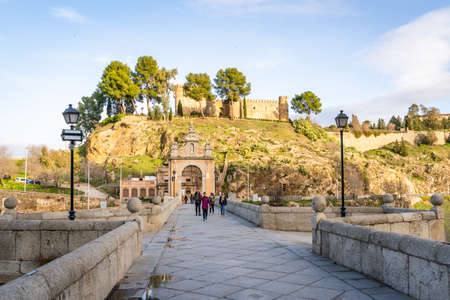 Toledo / Spain - January 23rd, 2020 Tourists Walking over Alcantara Bridge on Sunny Dayのeditorial素材