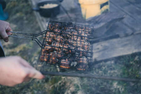 Holding grid with Grilled Meat in Hand - Beginning of Grill Season