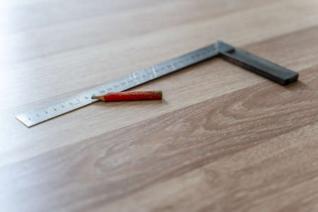 Red Carpenter's Pencil and Right Angle's Tool on Laminate Floor after Renovation or Reconstruction Work. DIY Projectの写真素材