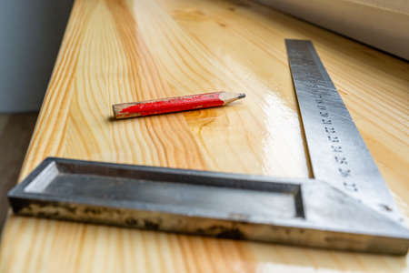 Red Carpenter's Pencil and Right Angle's Tool on Laminate Floor after Renovation or Reconstruction Work.- Selective Focusの写真素材
