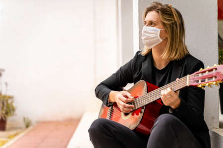 Young Caucasian Girl Wearing White Face Mask, Plays Red Guitar, Mockup. Business Outfitの写真素材