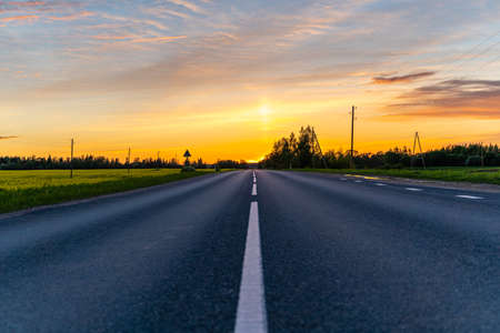 Empty Countryside Highway Road on Warm Summer Evening in Sunset Colors with Green Fields Aroundの写真素材