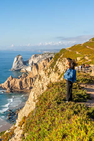 Smiling Young Girl Stands on Edge of Cabo da Roca - Westernmost Continental Europe Pointの写真素材