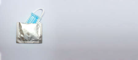 Surgical mask in silver packaging. Safe lifestyle. Protection for yourself and others. Selective focus. Mouth protection inside condom wrap.の写真素材