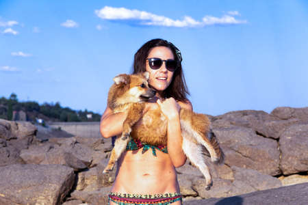 Young woman with her pomeranian dog in her arms in nature.の写真素材
