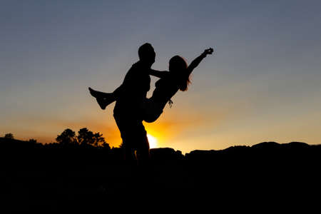 Boy holding girl in his arms at sunset in autumn. Copy space. Backlight. Sees it.の写真素材