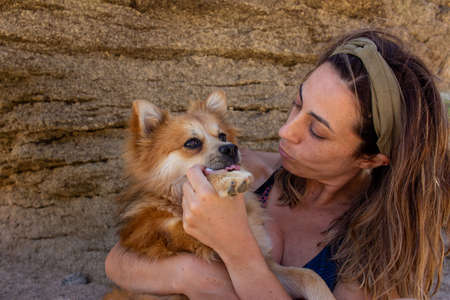 Blonde woman with headband in nature playing with her dog. Selective focus. Copy space.の写真素材