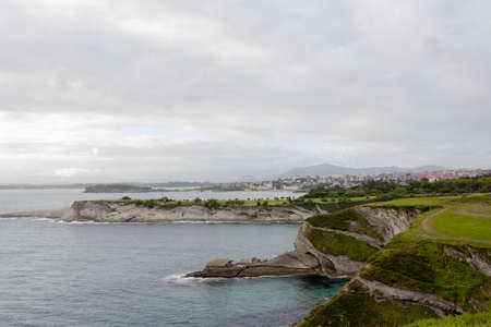 Sunset on a cliff facing the sea on a cloudy day with the city of Santander (Spain) in the background. Selective focus.の写真素材
