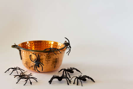 Old cauldron with toy spiders. Halloween background. Selective focus. Copy space.