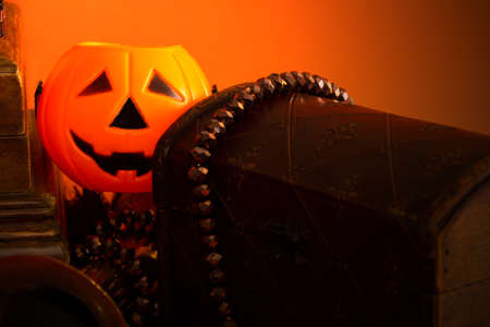 Decorative halloween still life with jewelry box, jack-o-lantern pumpkins, spiders, and vintage objects on orange background. Selective focus. Copy space.の写真素材