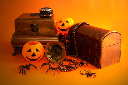 Decorative halloween still life with jewelry box, jack-o-lantern pumpkins, spiders, and vintage objects on orange background. Selective focus. Copy space.の写真素材