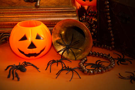 Decorative halloween still life with jewelry box, jack-o-lantern pumpkins, spiders, and vintage objects on orange background. Selective focus. Copy space.の写真素材