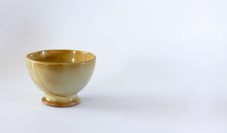 Light brown ceramic bowl varnished on white background. Selective focus. Copy space.の写真素材