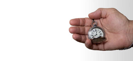 Man's hand holding a vintage pocket watch. Concept of time and work. Copy space. Isolated on white background. Selective focus.の写真素材