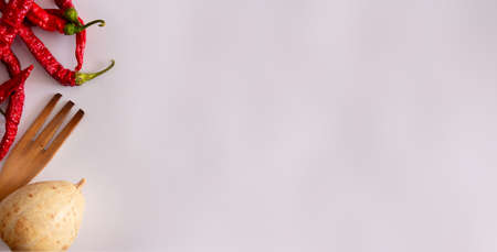 Thin red peppers with wooden fork and dried pumpkin on white background. Top view. Flat lay. Copy space.の写真素材