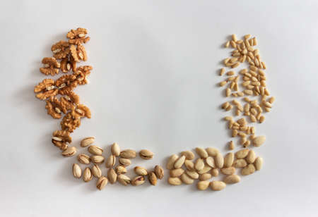 Nuts frame with walnuts, peanuts, almonds and pine nuts on white background. Copy space.
