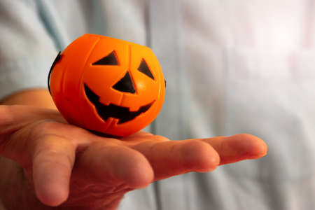 Hand carrying basket of halloween pumpkin candies. Selective focus. Copy space.の写真素材