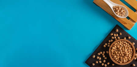 Chickpeas in cork bowl and slate surface with porcelain spoon on blue background. Flat lay. Copy space.の写真素材